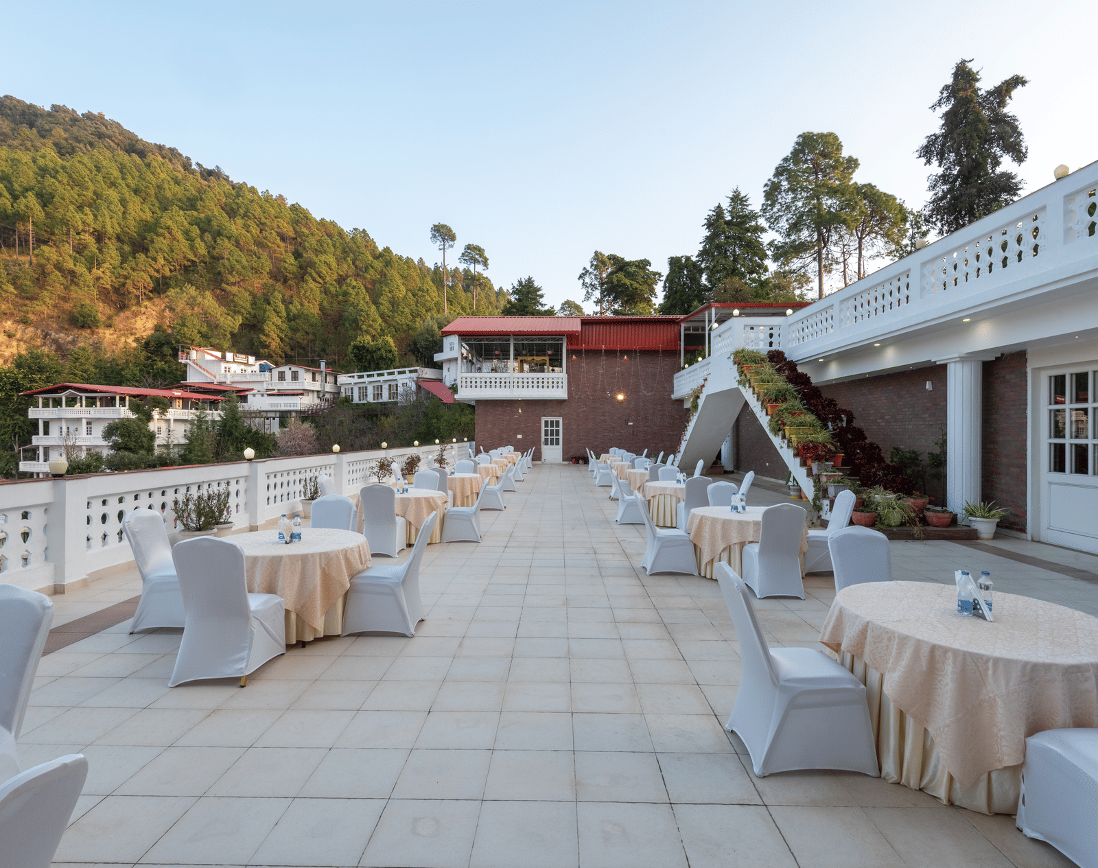 A spacious outdoor terrace with chairs at DLS Tehri Club Resort with stunning views of the surrounding mountains